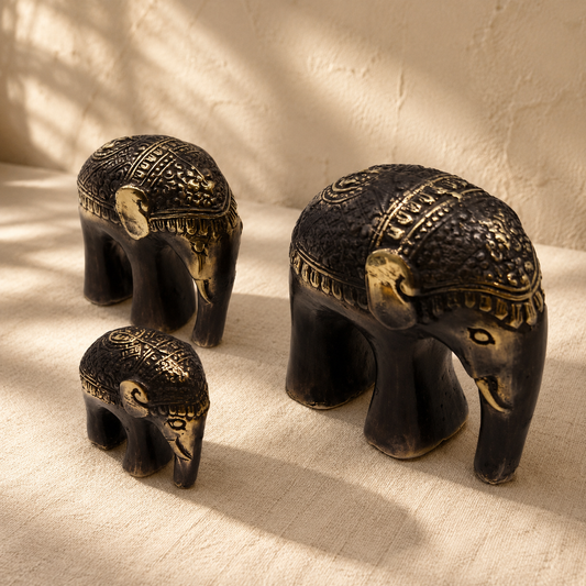 Éléphants décoratifs Amara noir et doré présentés sur un textile beige