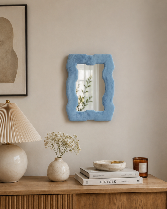 Miroir Alma Bleu azur en velours installé au mur dans un intérieur chaleureux