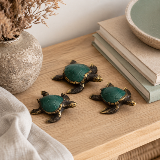 Tortues décoratives Kaïa en laiton vert et doré disposées sur une table en bois dans une mise en situation chaleureuse.