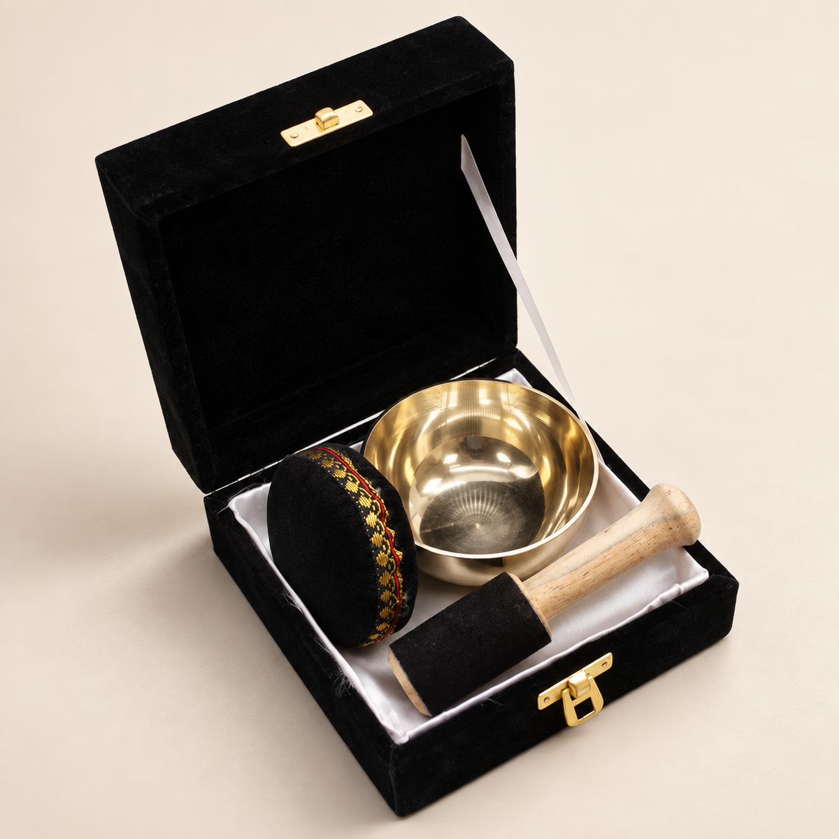 Coffret noir ouvert contenant le bol chantant Svara en laiton et ses accessoires.
