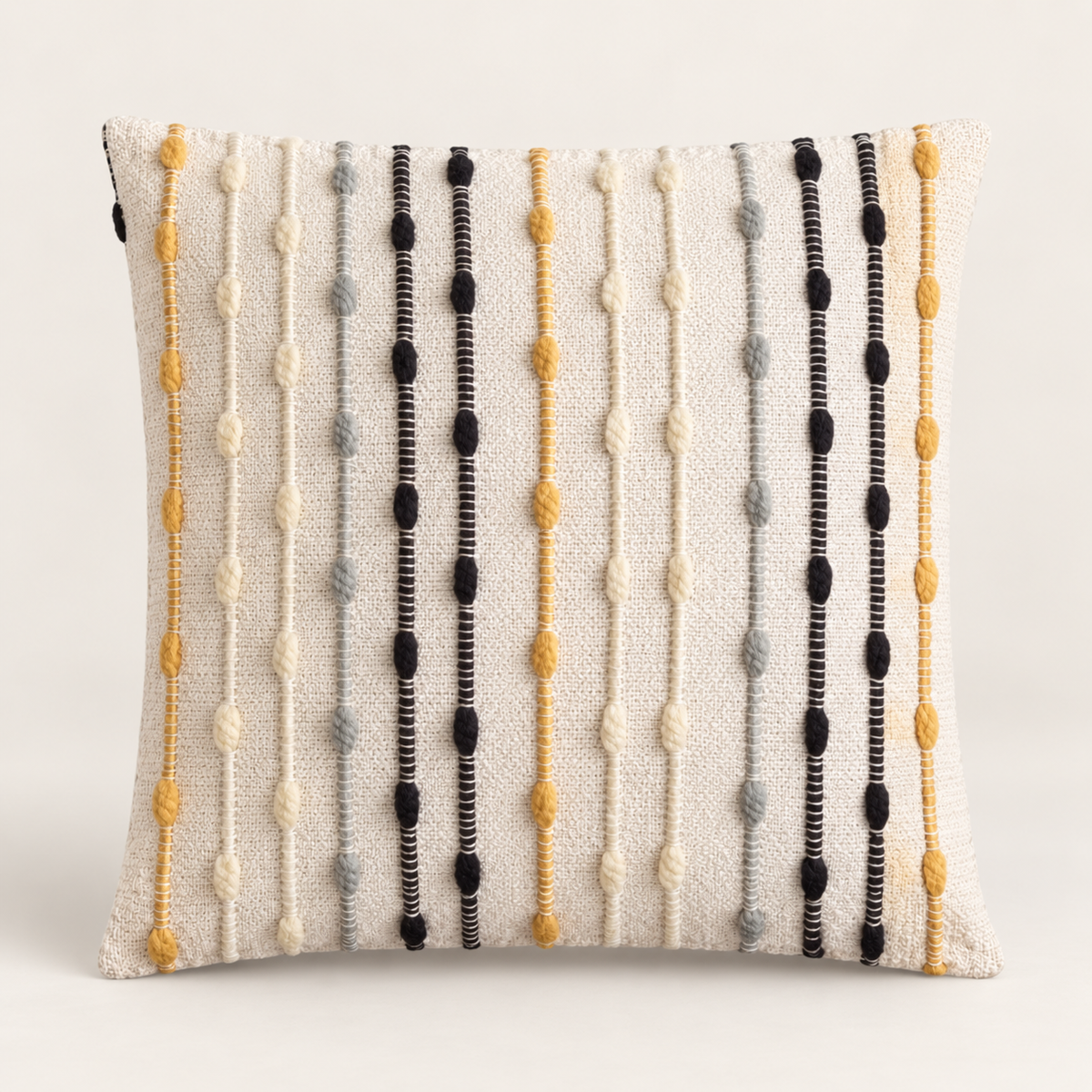 Housse de coussin Maïra 45 × 45 cm présentée de face, avec fond écru, lignes verticales moutarde, grises et noires et détails texturés en relief.