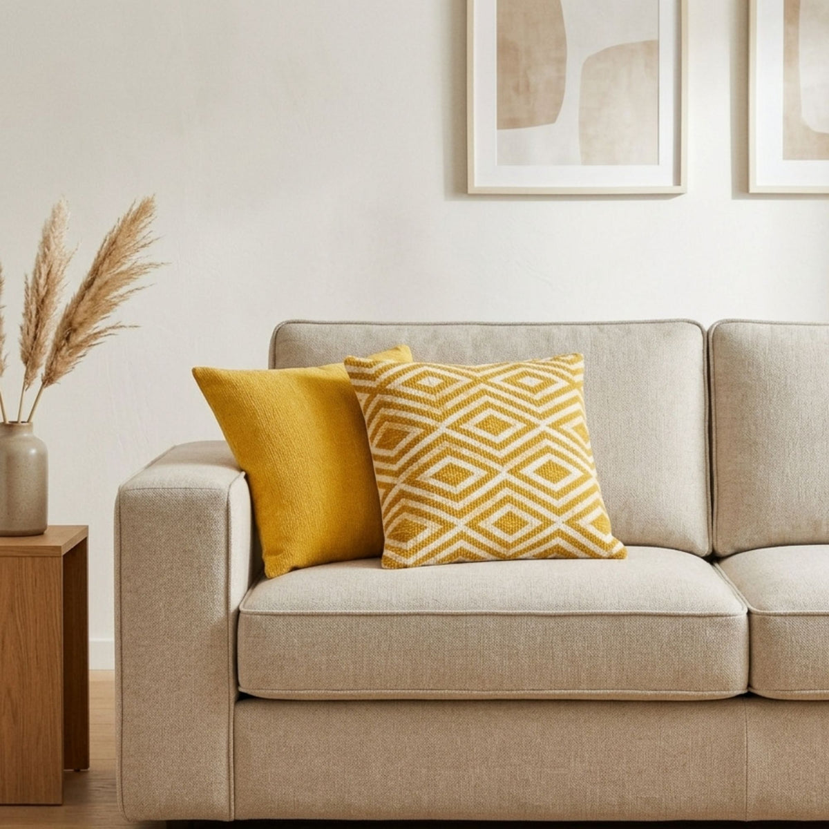 Housse de coussin Naëla 45 × 45 cm disposée sur un canapé clair avec coussins moutarde pour une ambiance chaleureuse.