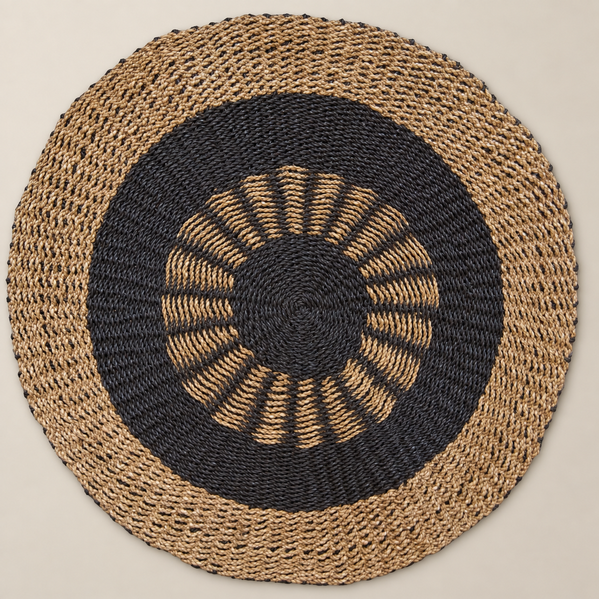 Vue de dessus du tapis rond Soléa Ø 100 cm en jonc de mer naturel et charbon avec motif solaire graphique.