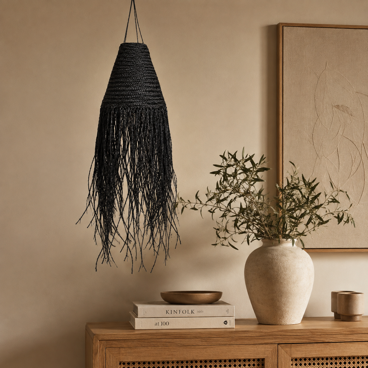 Abat-jour Sanaa en fibres noires tressées suspendu au-dessus d’une console en bois dans un intérieur chaleureux.