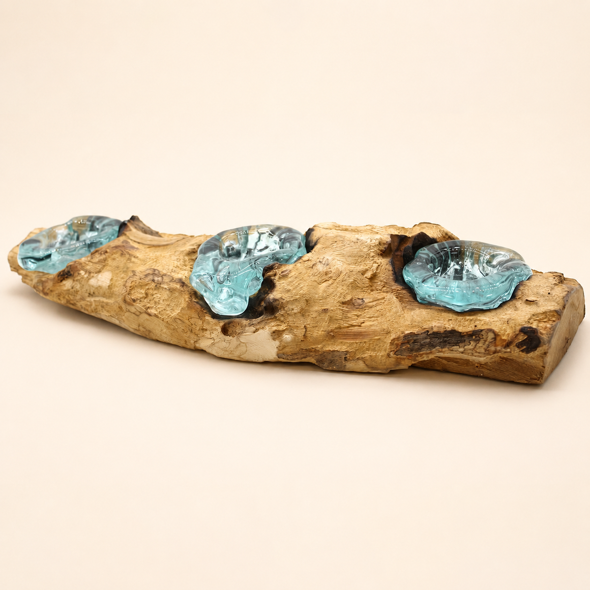 Bougeoir Néria Trio vu en angle, avec trois coupelles en verre bleu-vert façonnées sur une pièce de bois Gamal naturel.