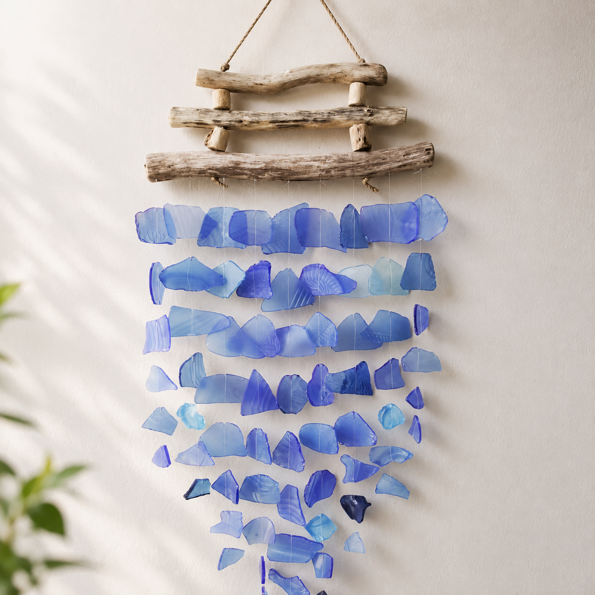 Carillon Azura en verre recyclé bleu et bois flotté suspendu sur fond neutre.