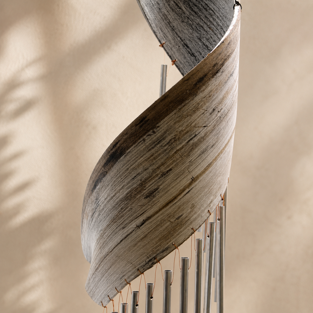 Détail de la feuille de cocotier torsadée et des tubes métalliques du carillon Malia.