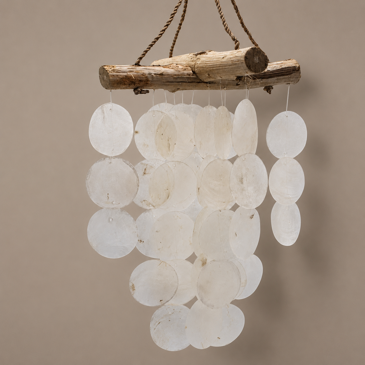 Carillon Perla en Capiz blanc et bois flotté présenté sur un fond neutre contrasté.