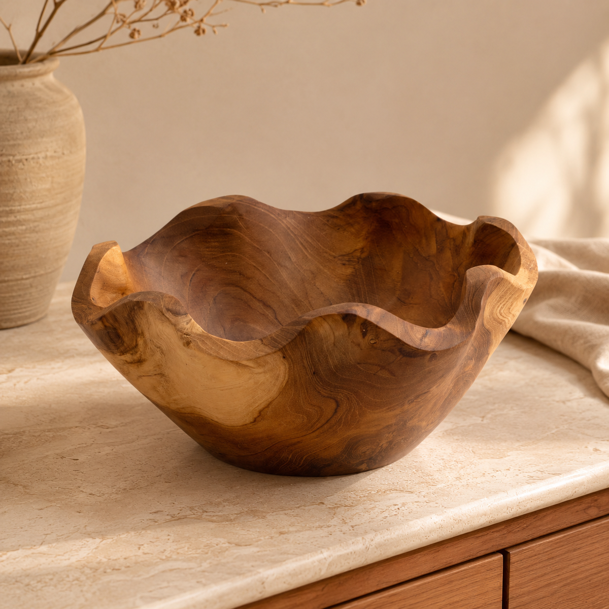 Corbeille Naya en teck naturel aux bords ondulés, posée sur une console dans un intérieur chaleureux