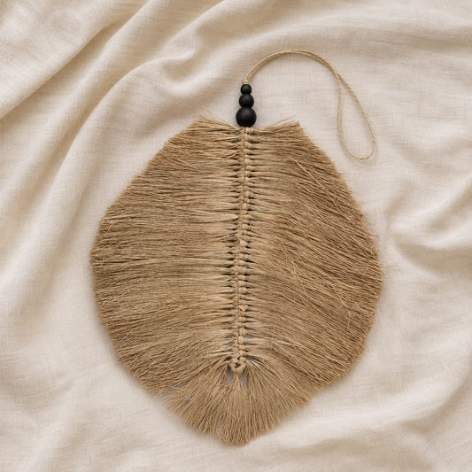 Feuille décorative murale Aïna en raphia naturel posée à plat sur un tissu beige