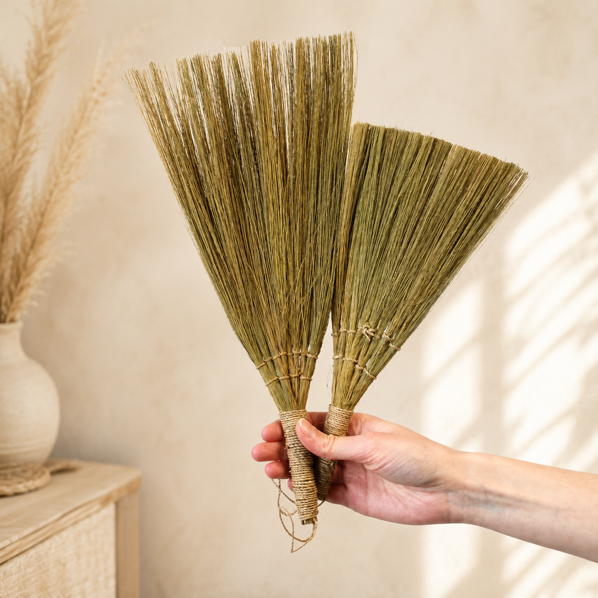 Deux éventails Nayra tenus à la main pour montrer leur format, leur texture et leurs nuances naturelles.