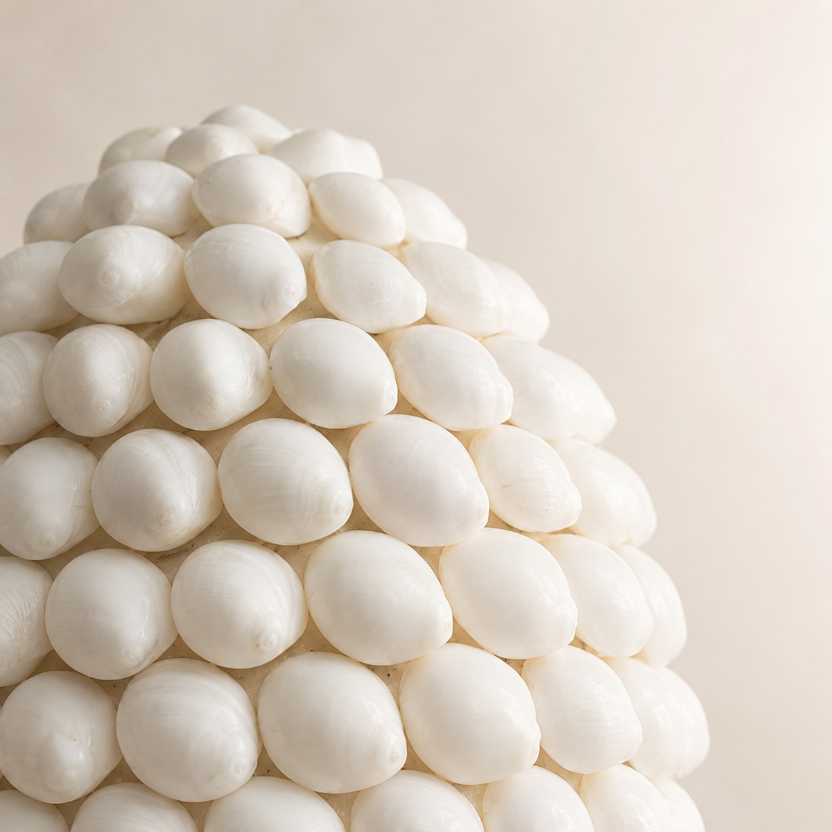 Gros plan sur les coquillages naturels ivoire de la lampe Nacréa, montrant leur relief délicat et leur disposition artisanale.