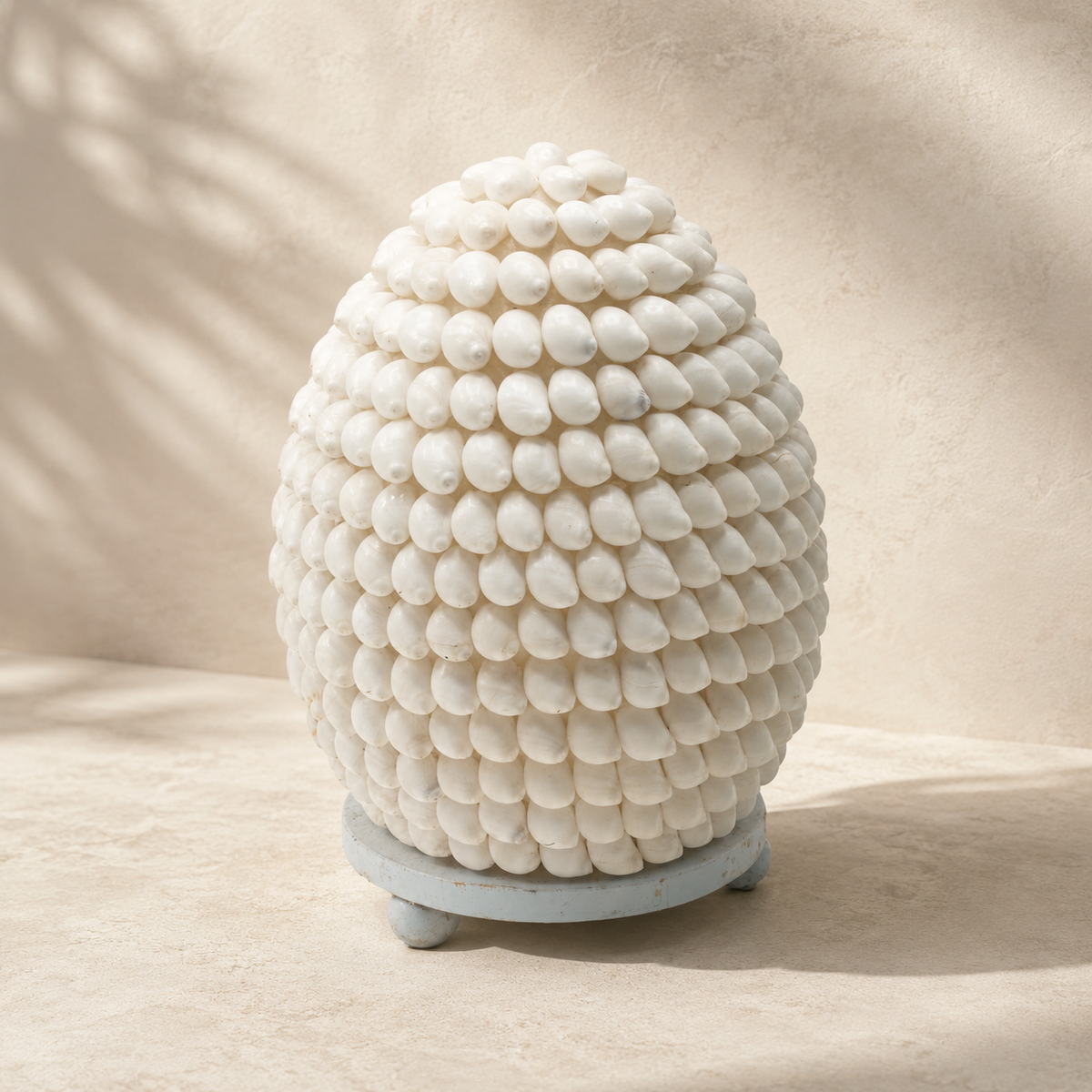 Lampe Nacréa en coquillages naturels ivoire posée seule sur un fond neutre, mettant en valeur sa forme arrondie et sa texture artisanale.