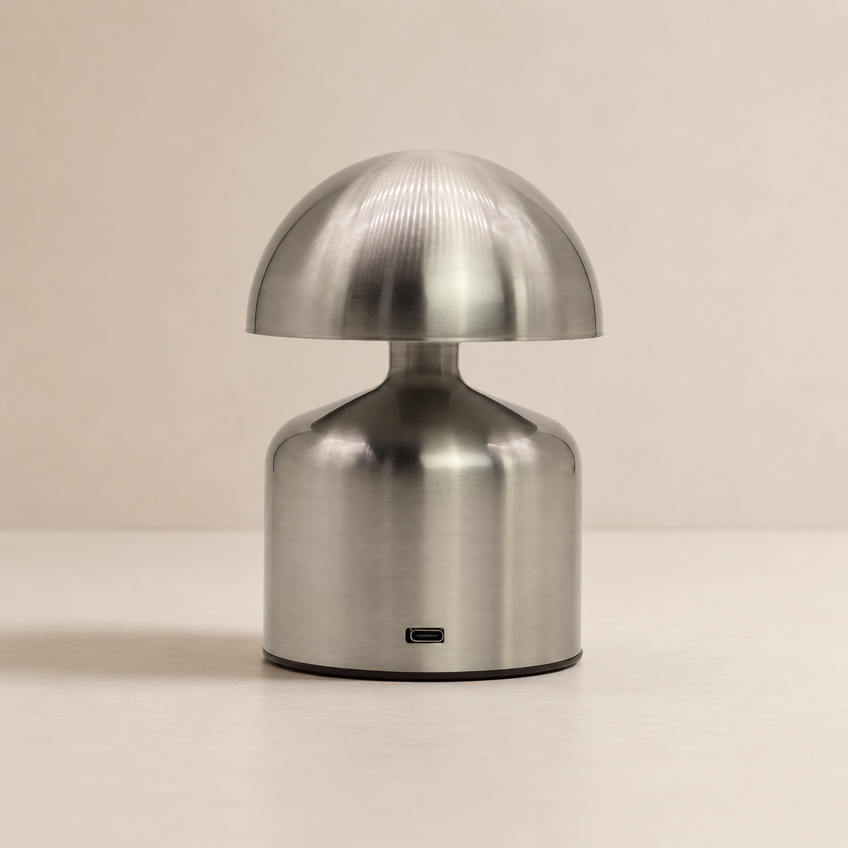 Lampe Noma argent vue de face avec port USB-C visible sur fond beige neutre.