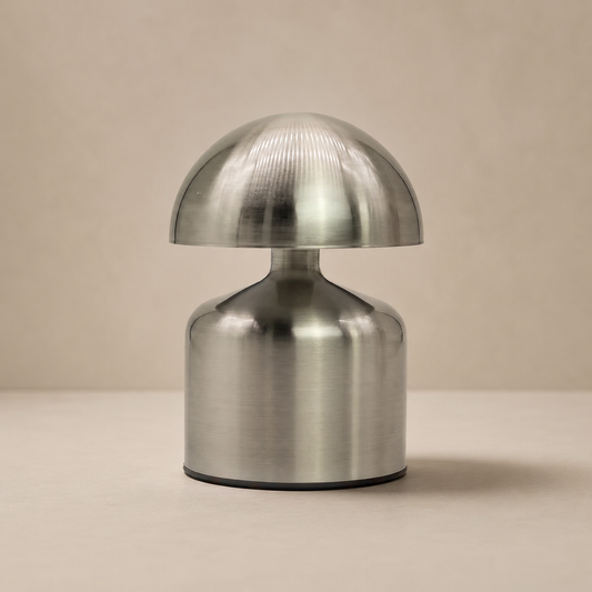 Lampe Noma argent vue de face sur fond beige neutre, mettant en valeur sa silhouette arrondie en métal.