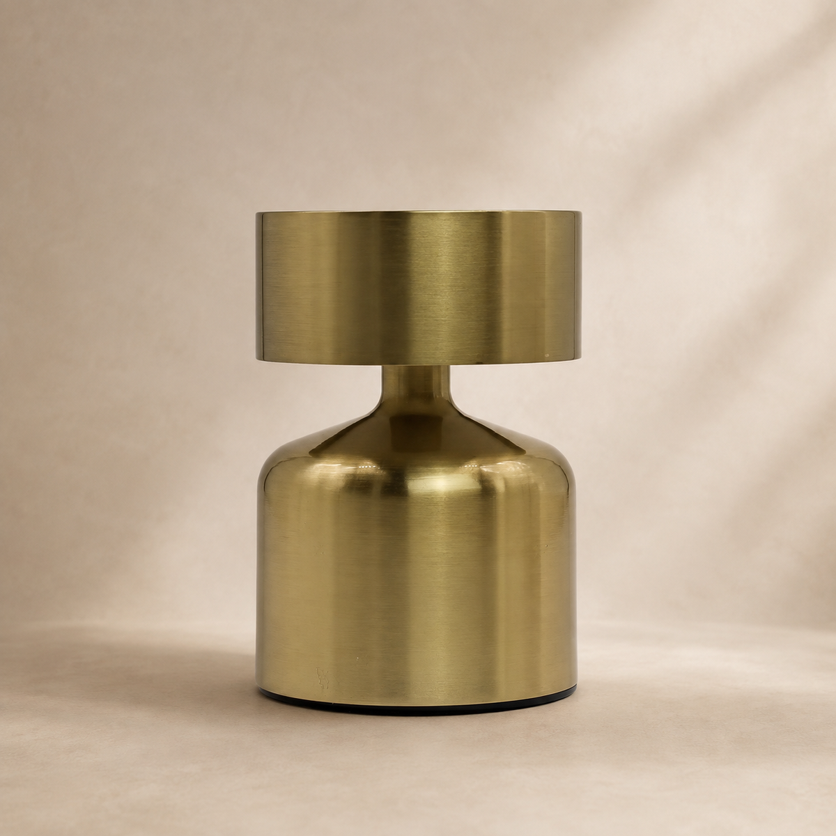 Lampe Noma bronze vue de face sur fond beige, au design compact et minimaliste.