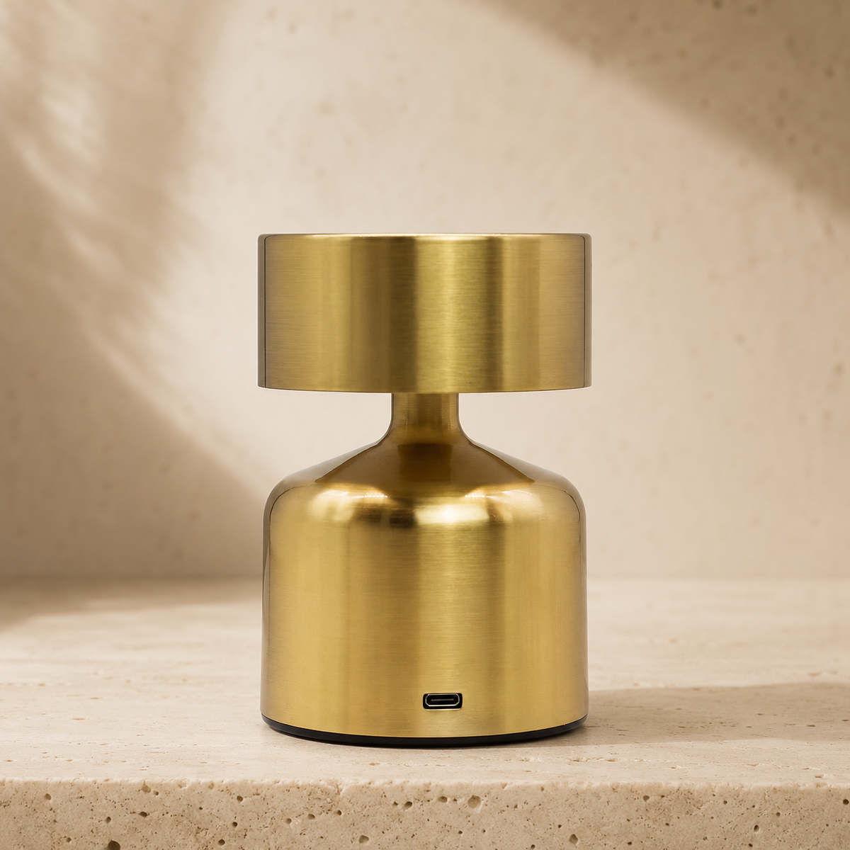 Lampe Noma bronze vue de face avec port USB-C visible, posée sur une surface minérale claire.