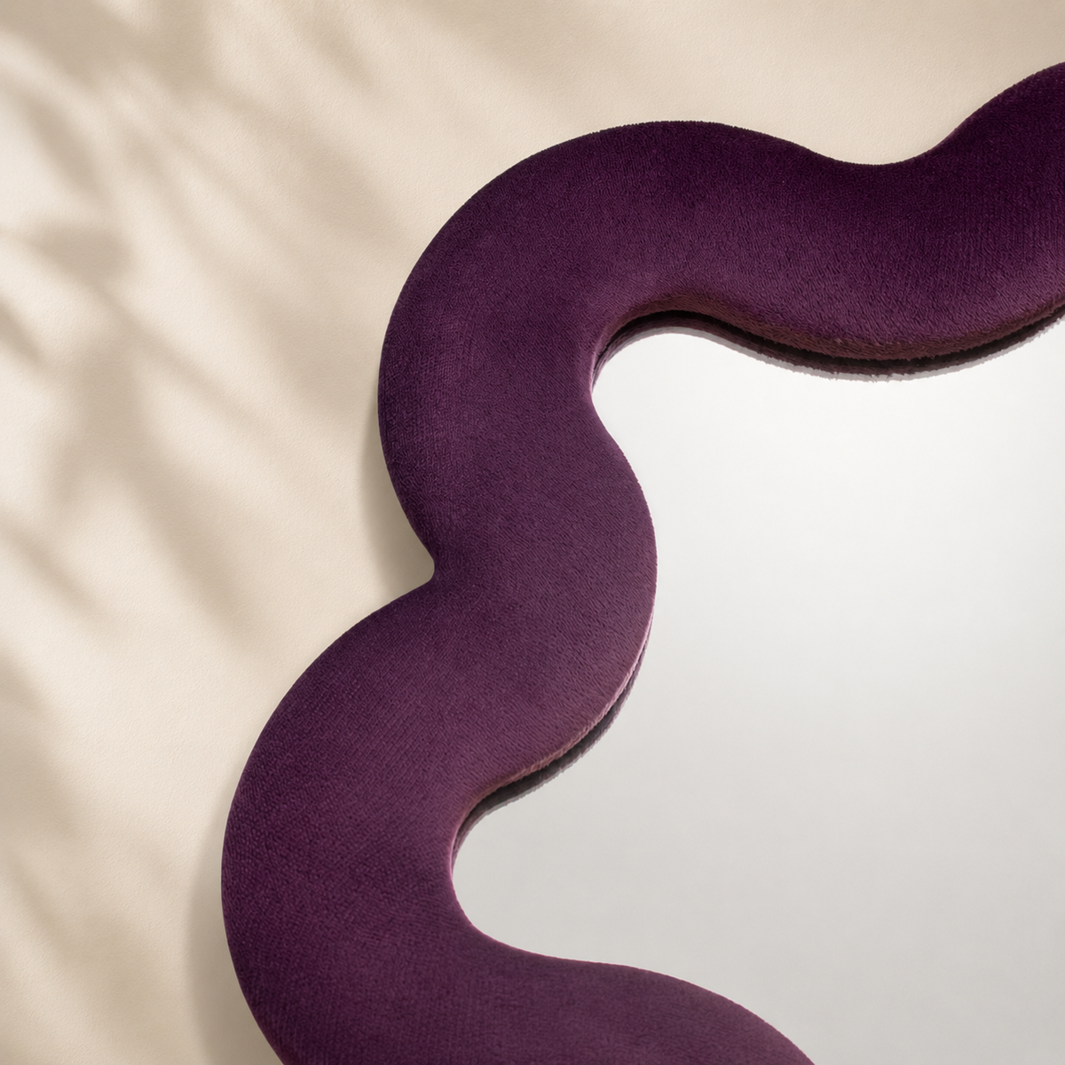 Gros plan sur le cadre ondulé en velours prune du miroir Alma