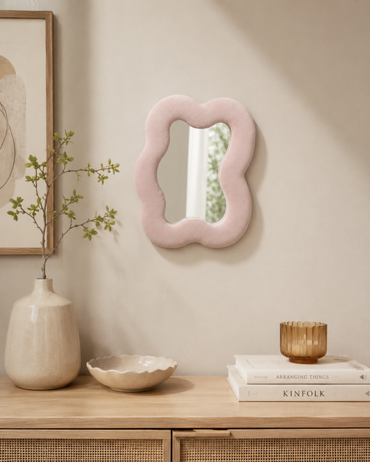 Miroir Alma Rose poudré en velours installé au mur dans un intérieur chaleureux