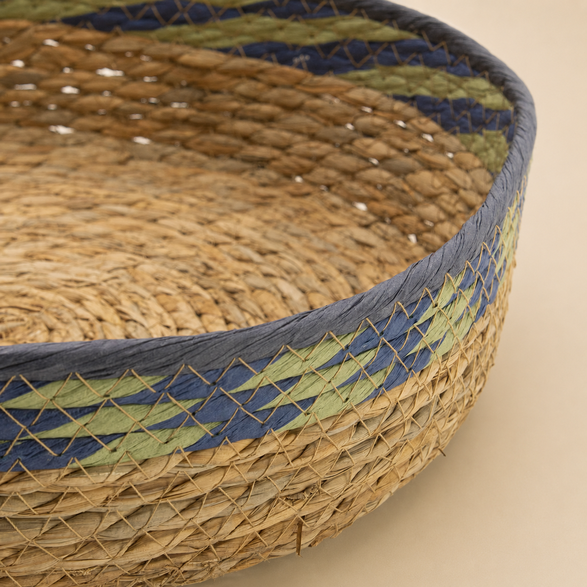 Gros plan sur le tressage en fibres naturelles et les détails verts et bleus du panier Sélia.