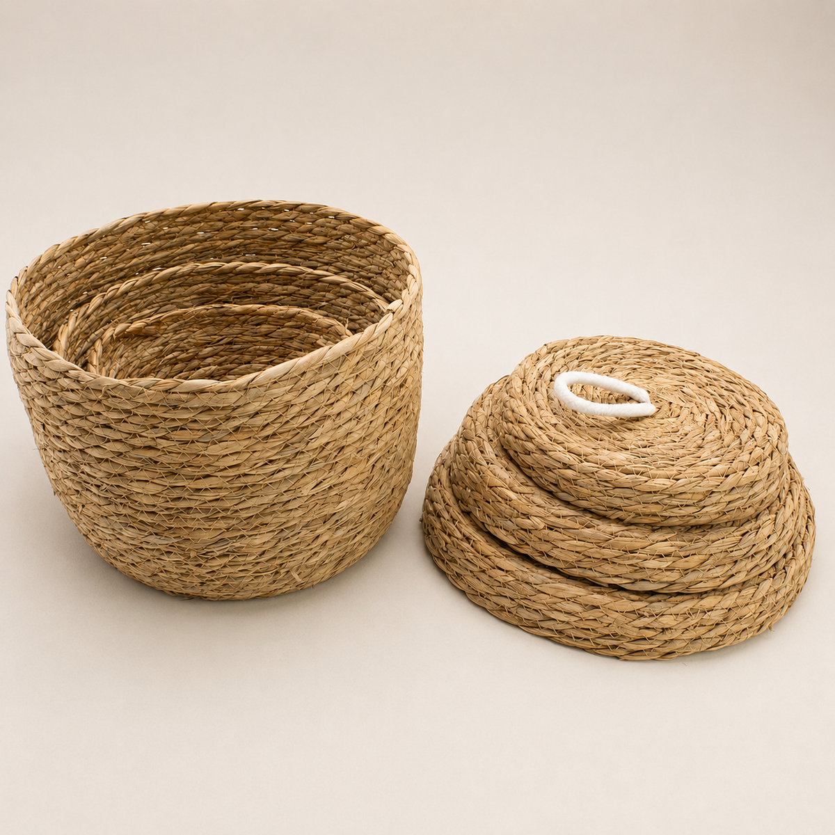 Paniers Liora de différentes tailles imbriqués avec leurs couvercles en fibres naturelles tressées.