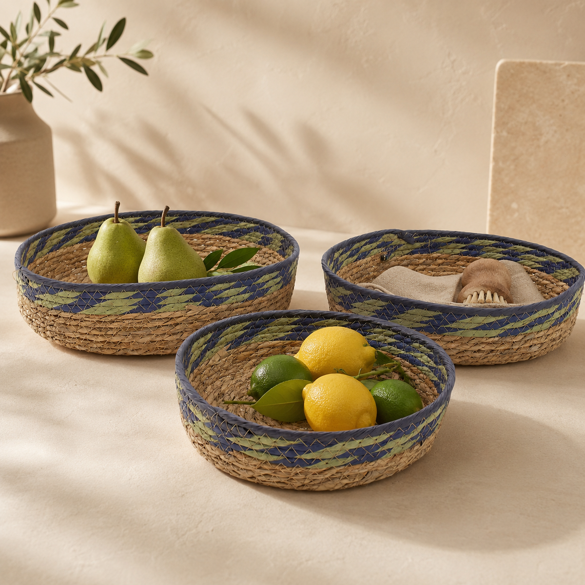 Trio de paniers Sélia en fibres naturelles tressées, rehaussés de détails verts et bleus, présenté dans une ambiance chaleureuse.