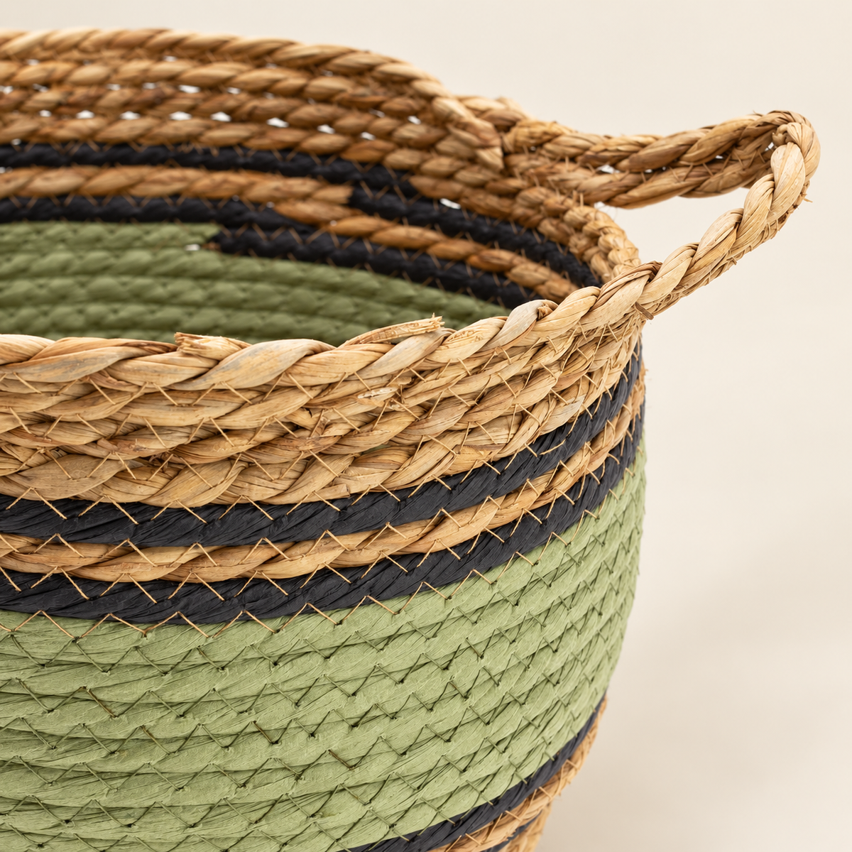 Détail du tressage naturel des paniers Vahéa avec bandes vertes et noires et poignée intégrée.