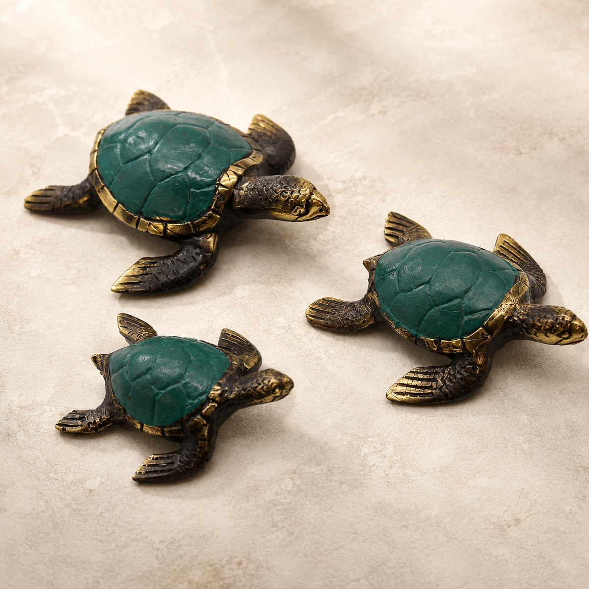 Trio de tortues décoratives Kaïa en laiton vert et doré sur fond neutre.