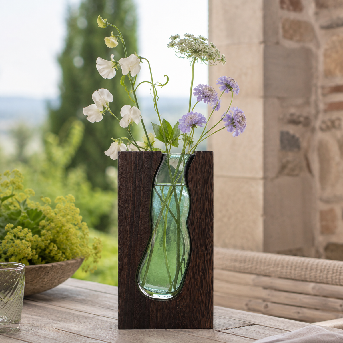 Vase Elwen 32 cm en verre et bois foncé mis en scène avec des fleurs dans un décor naturel
